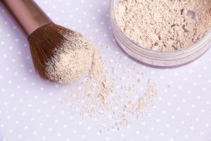 mineral Makeup powder and a powder brush on a purple background, soft bedding colors, close up