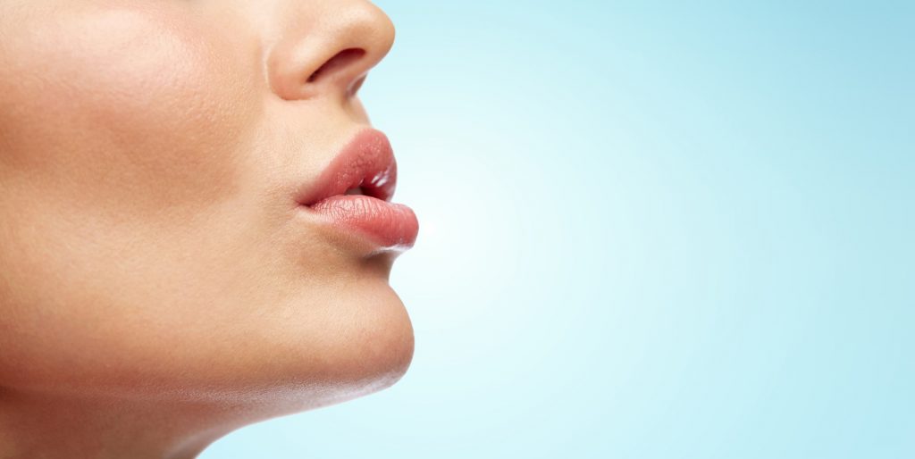 close up of young woman lips over blue