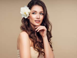 brunnette female model with a flower in her hair again a tan background